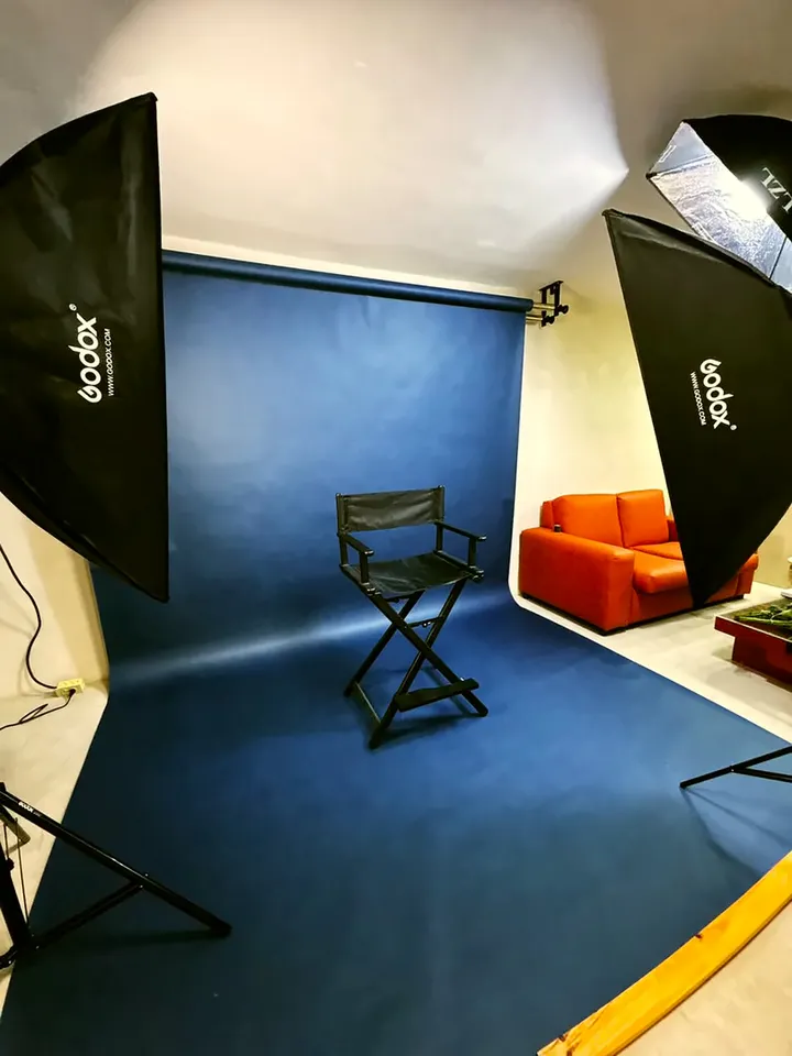Fondo azul continuo con una silla de director y dos softbox encendidos.
